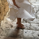 Person wearing a white dress descending stone steps.