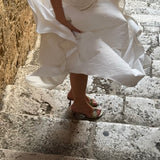 Person wearing a white dress descending stone steps.