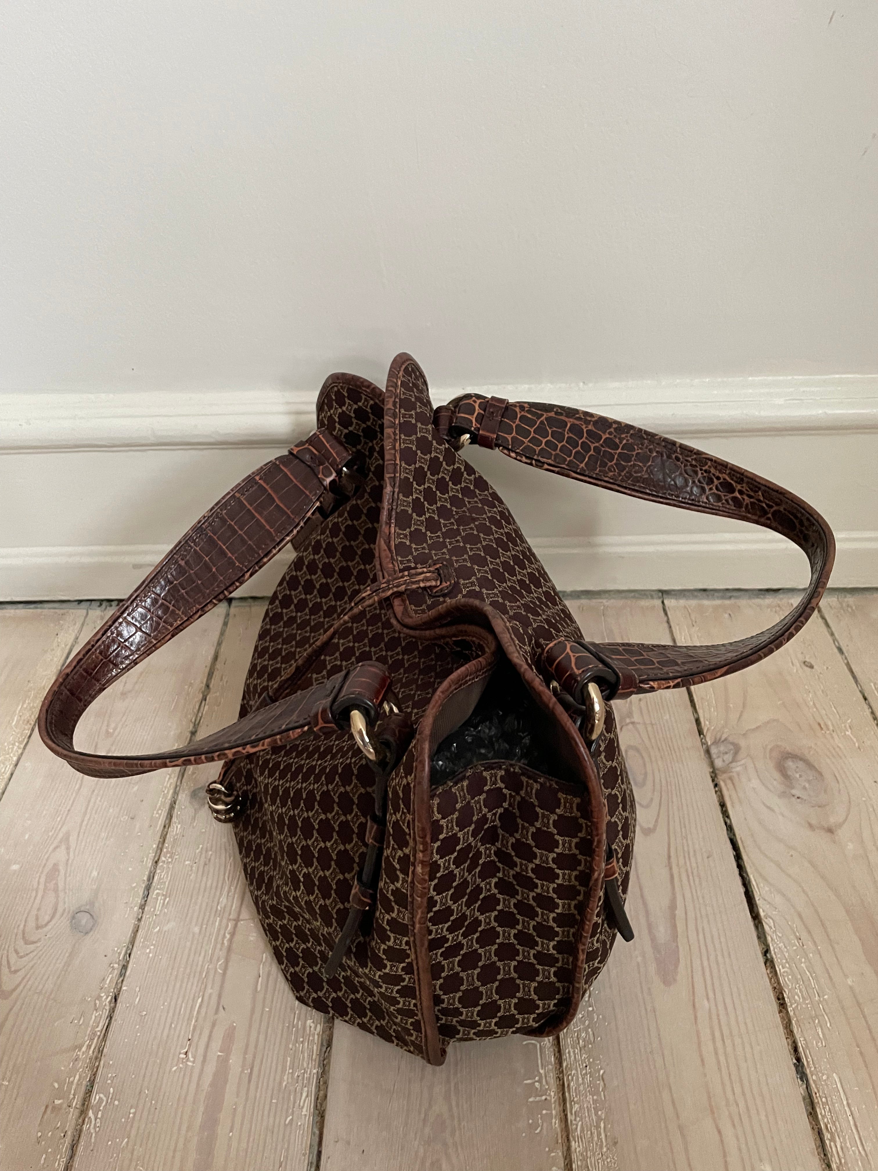 This is a Celine Macadam Bitter Sweet handbag, showcasing the brand's iconic macadam pattern. The bag features a combination of brown canvas and croc-embossed leather details, accentuated by gold-tone hardware.&nbsp;