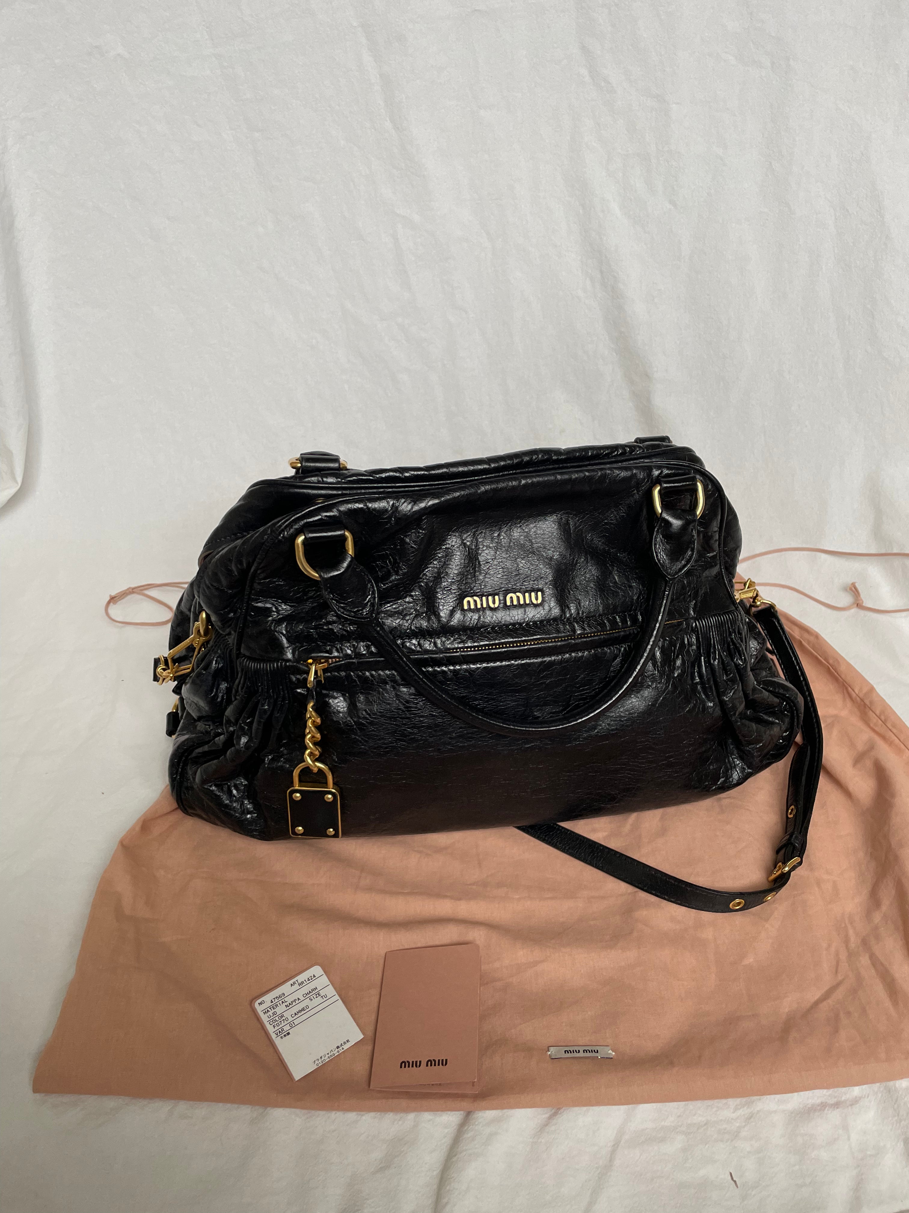 Miu Miu black nappa leather bag in a very good condition.

Crafted from nappa leather, this handbag features luxurious material and gold-tone hardware. It includes a front zip pocket, a top zip closure, and an interior slip pocket. The bag has a gold padlock charm.