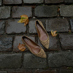 These vintage Coach ballet flats feature a pointed toe, lace-up details, and gold-tone eyelets along the edges. Crafted from beige suede with a smooth leather lining.