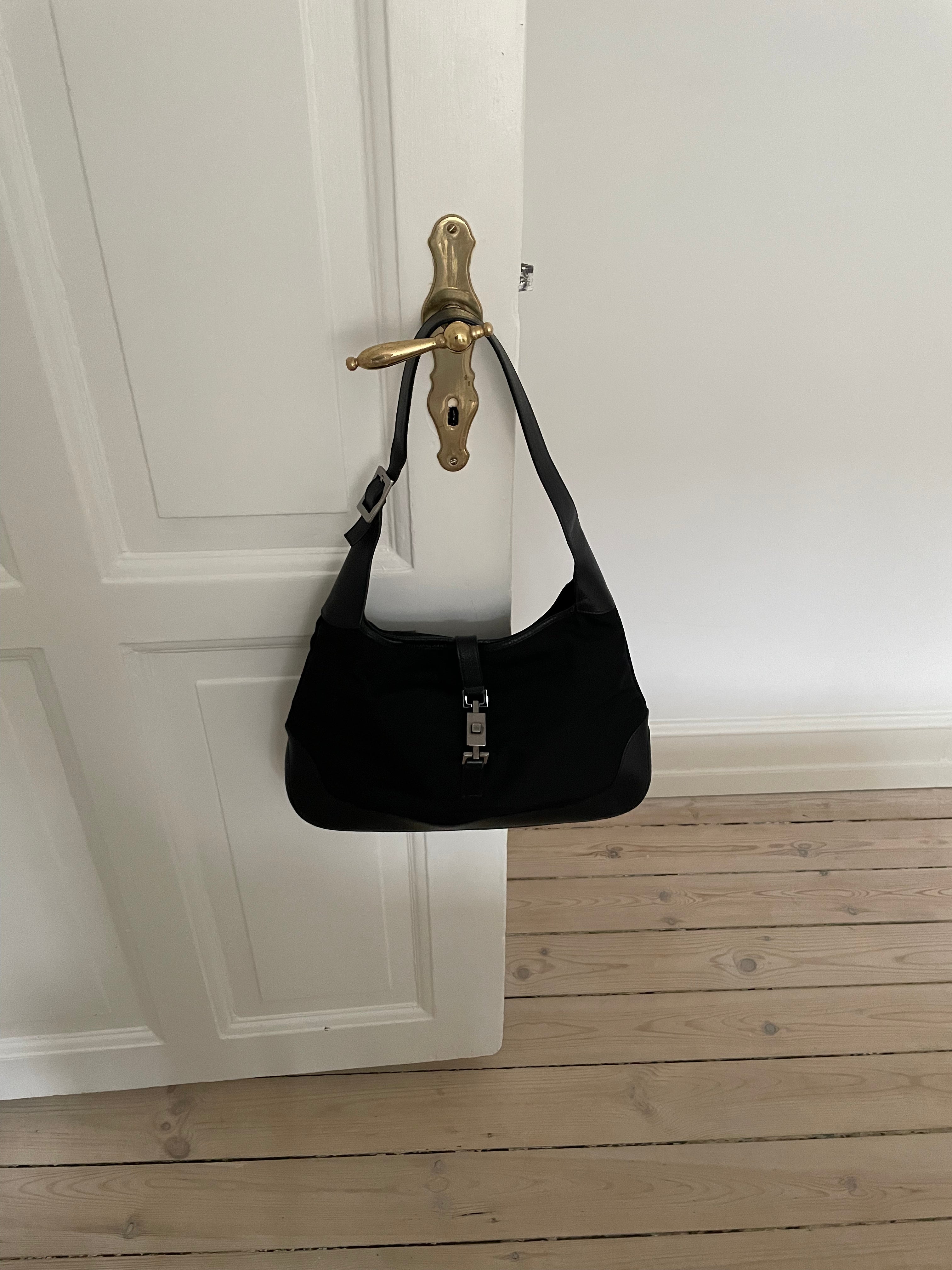 A vintage Gucci Jackie in black leather and nylon. The bag features a stylish buckle closure and a spacious interior. A timeless design perfect for any occasion.