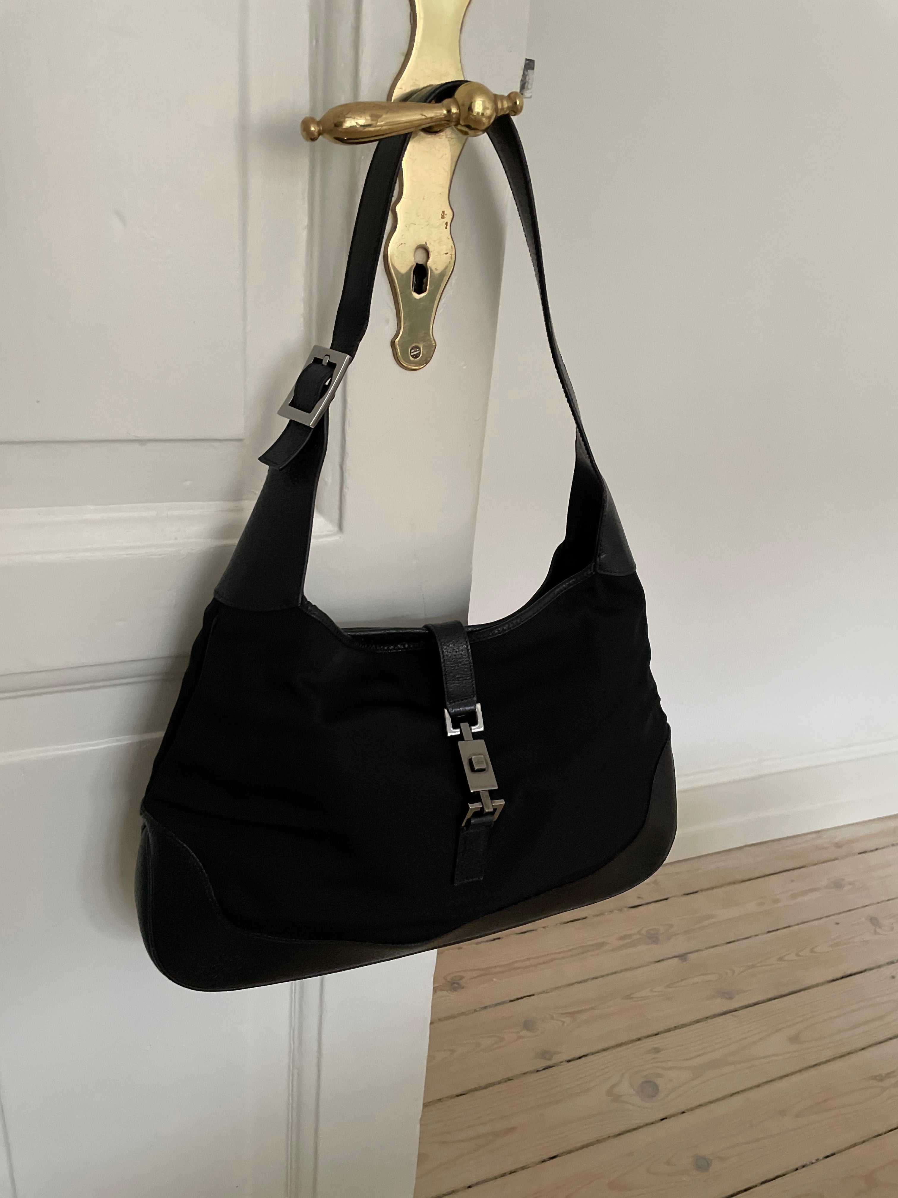 A vintage Gucci Jackie in black leather and nylon. The bag features a stylish buckle closure and a spacious interior. A timeless design perfect for any occasion.