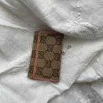 Gucci key wallet in iconic denim Gucci monogram and pink leather. The wallet shows signs of wear on the edges.