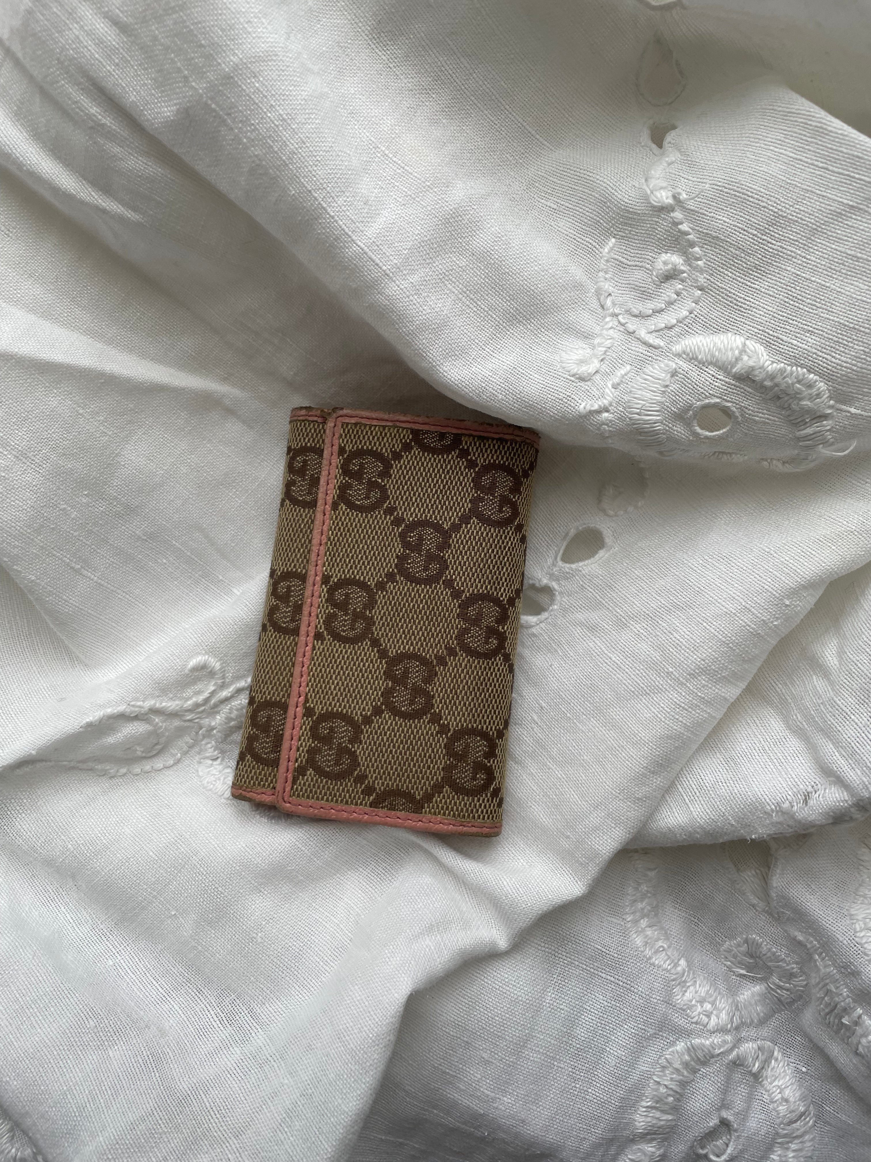 Gucci key wallet in iconic denim Gucci monogram and pink leather. The wallet shows signs of wear on the edges.