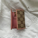 Gucci key wallet in iconic denim Gucci monogram and pink leather. The wallet shows signs of wear on the edges.