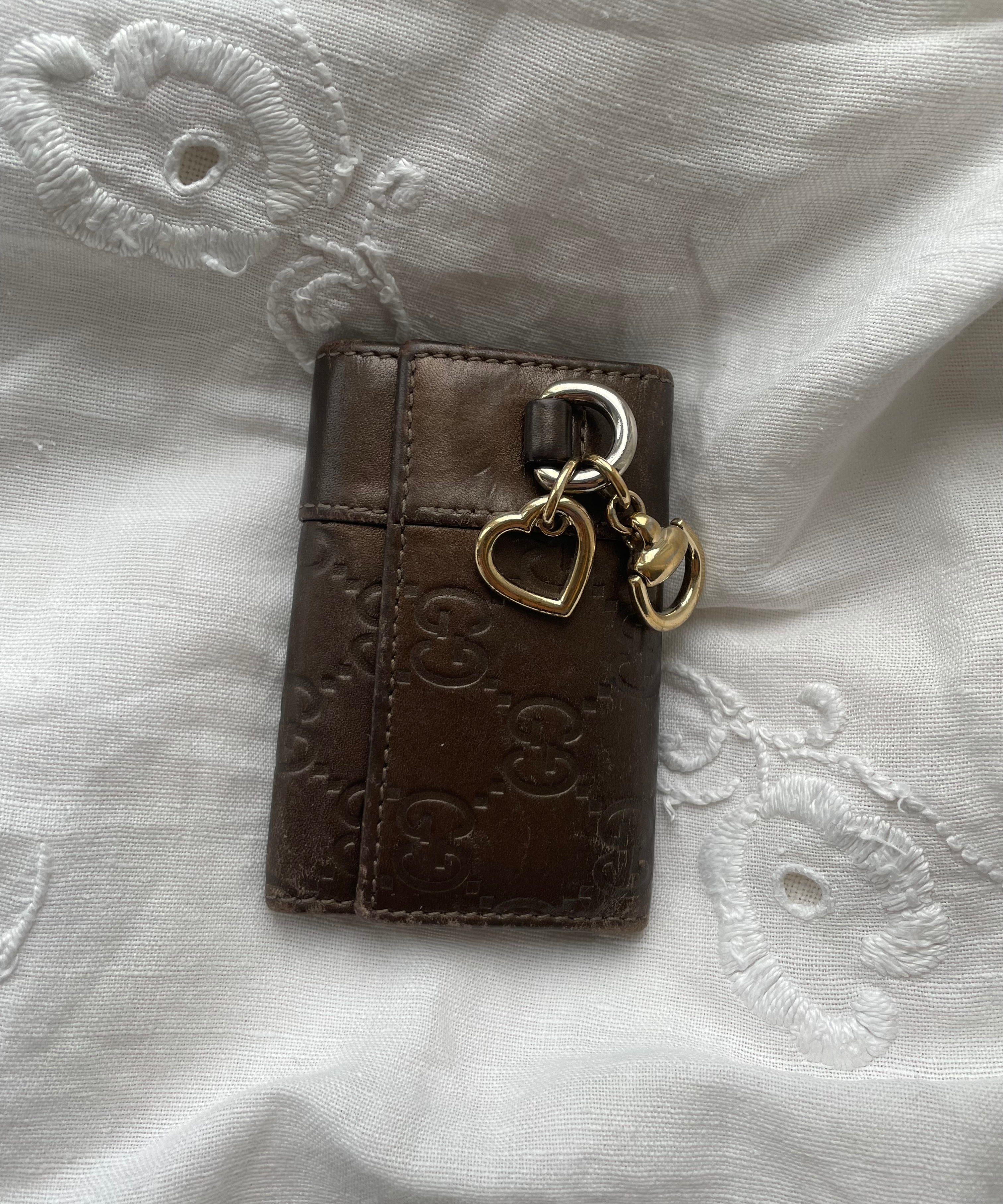 Gucci key wallet in brown leather with iconic monogram and a cute silver charm.
