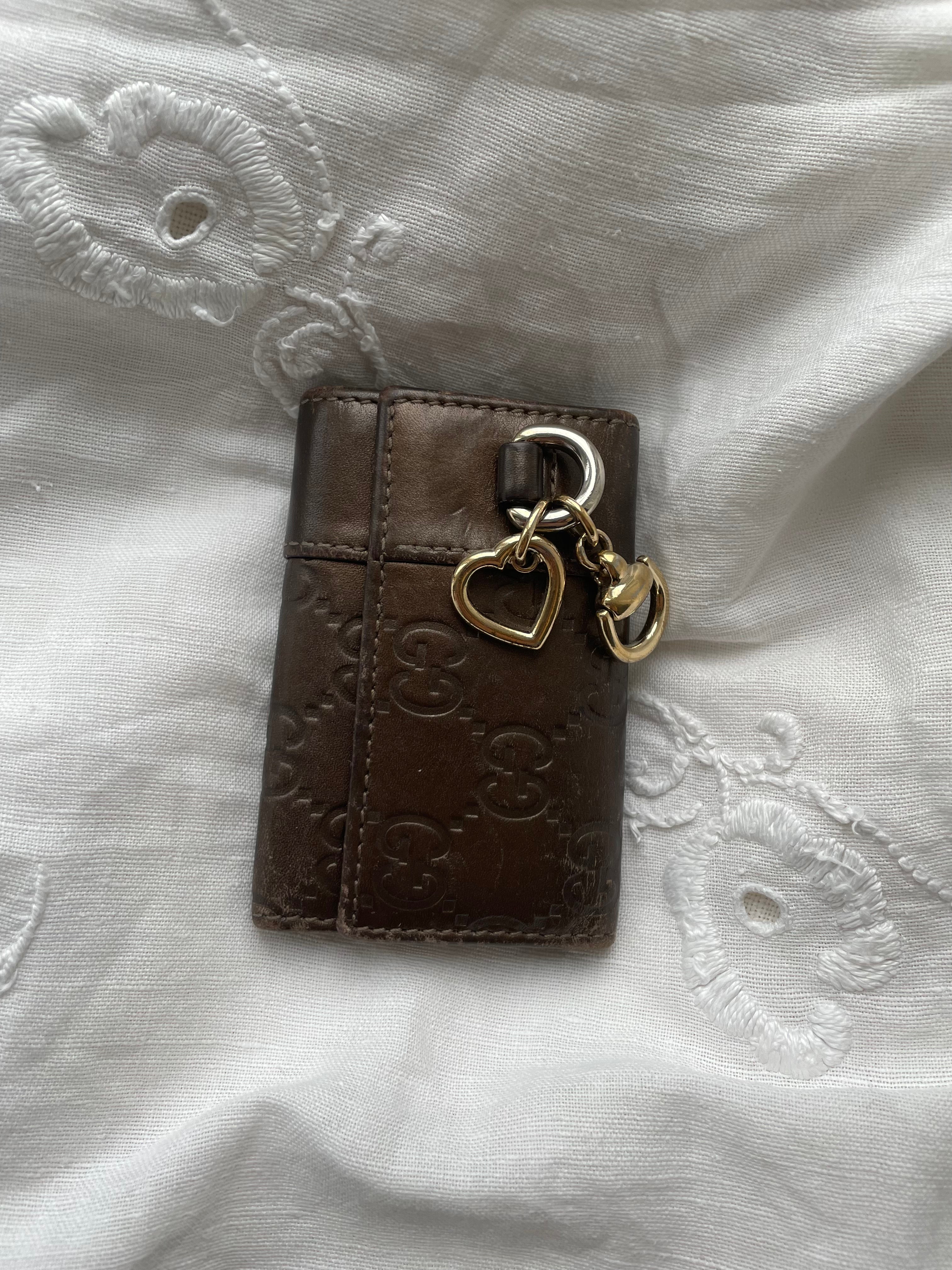 Gucci key wallet in brown leather with iconic monogram and a cute silver charm.