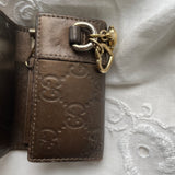 Gucci key wallet in brown leather with iconic monogram and a cute silver charm.