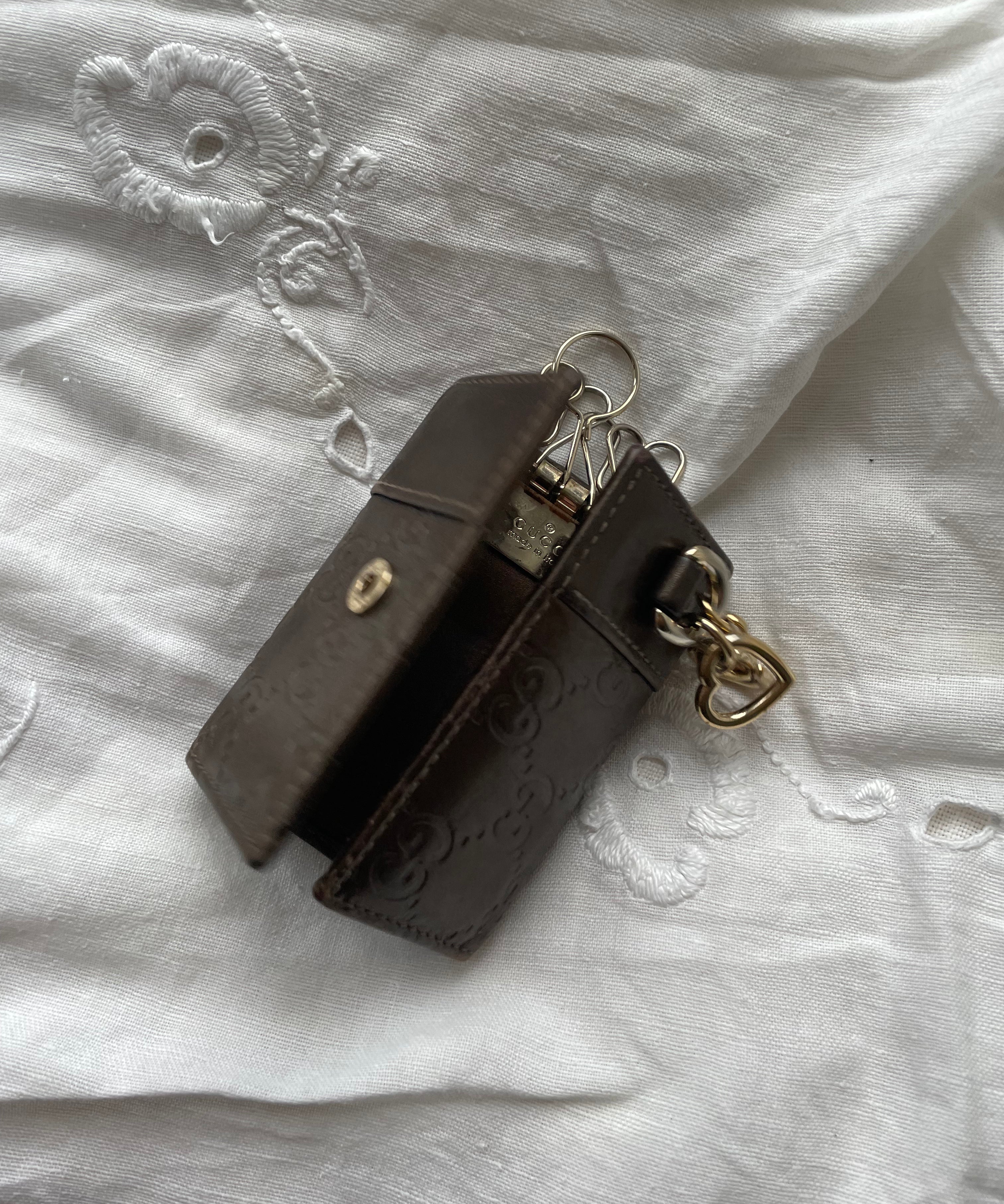 Gucci key wallet in brown leather with iconic monogram and a cute silver charm.