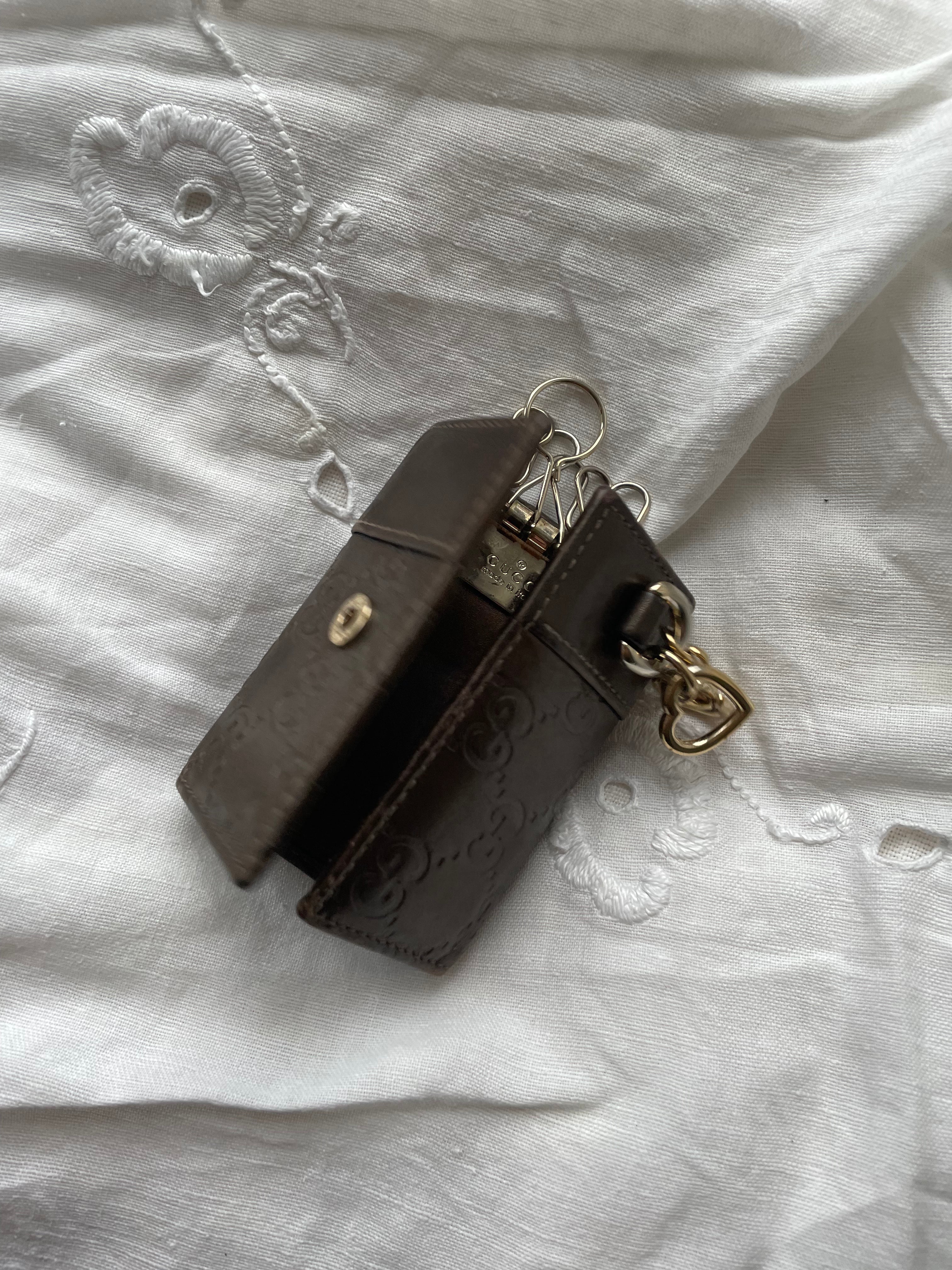 Gucci key wallet in brown leather with iconic monogram and a cute silver charm.