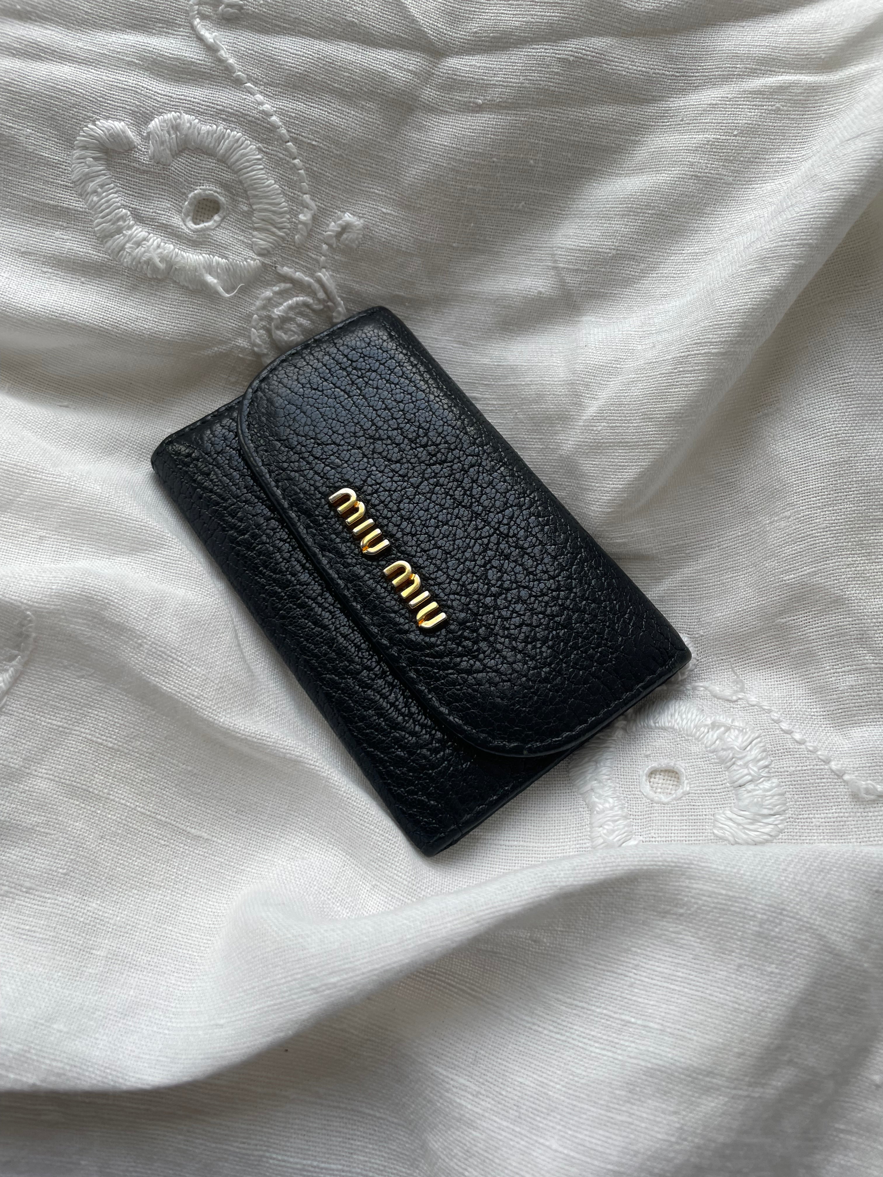 Miu Miu wallet in soft black leather with gold-colored hardware and room for 5 keys. The condition is rated 8/10, as one of the six key locks is missing, despite the wallet being in great overall condition.